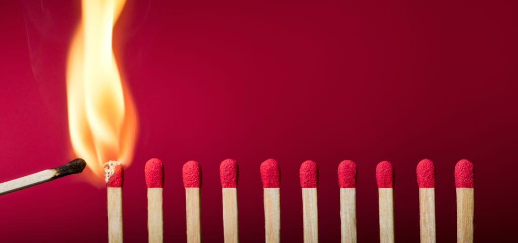 A lit match lighting a row of other matches